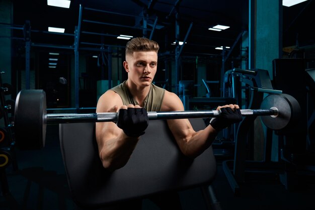 Homem musculoso treinando bíceps com barra