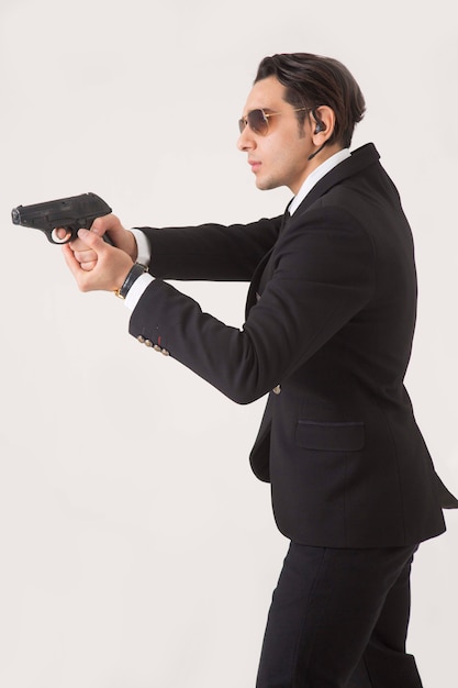 Foto grátis homem na suíte de negócios e arma no fundo branco