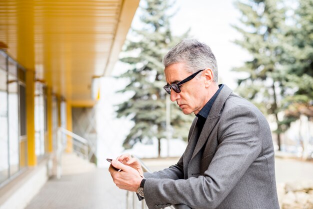 Homem negócios idoso, usando, telefone móvel, ao ar livre