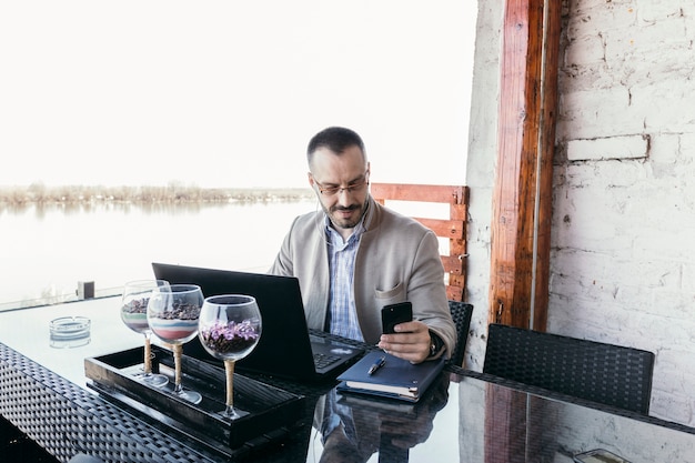 Homem negócios, percorrendo, smartphone, e, laptop, em, restaurante