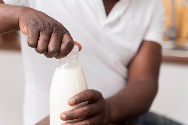Homem negro abrindo uma garrafa de leite