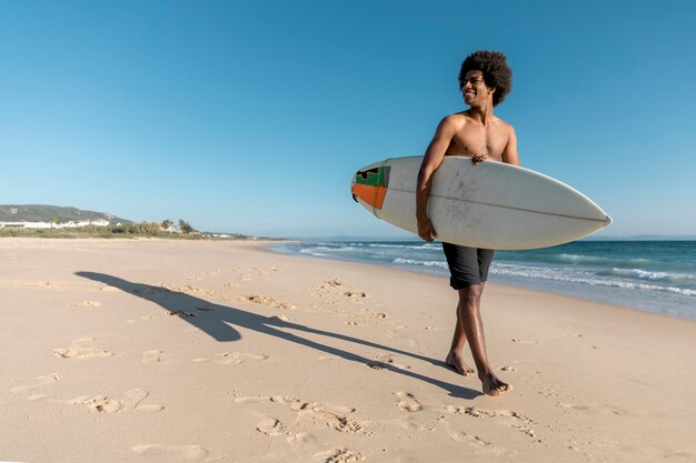 Homem negro, andar ao longo praia, com, surfboard