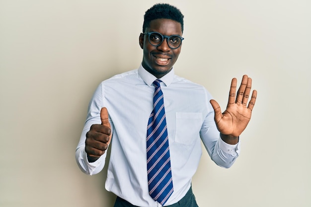 Foto grátis homem negro bonito vestindo camisa de negócios de óculos e gravata mostrando e apontando para cima com os dedos número seis enquanto sorria confiante e feliz.