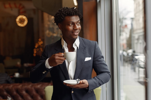 Homem negro de pé em um café e beber um café
