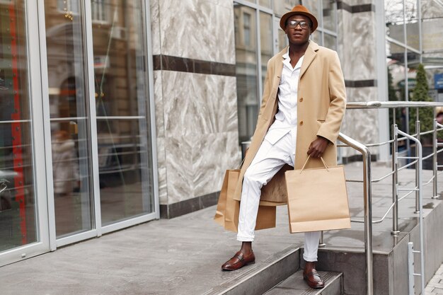 Homem negro elegante em uma cidade com sacolas de compras