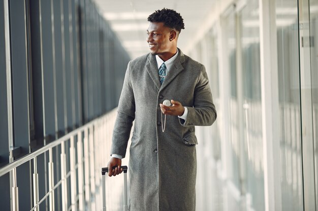 Homem negro elegante no aeroporto com uma mala