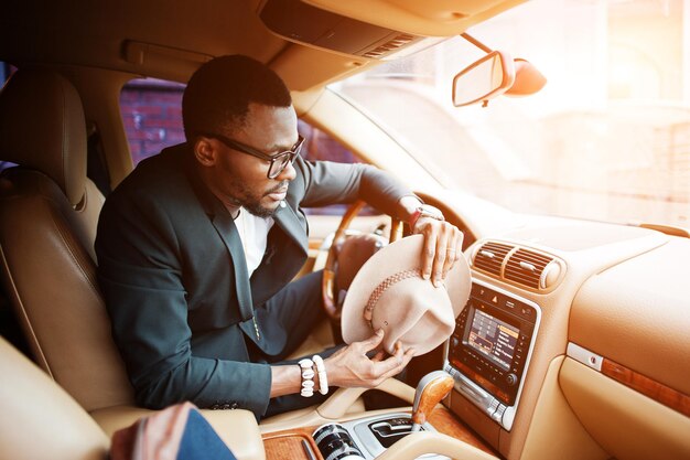 Homem negro elegante sentado ao volante do carro de luxo Rico empresário americano africano