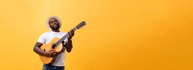 Homem negro musculoso tocando guitarra vestindo jeans e regata branca isolado sobre fundo amarelo