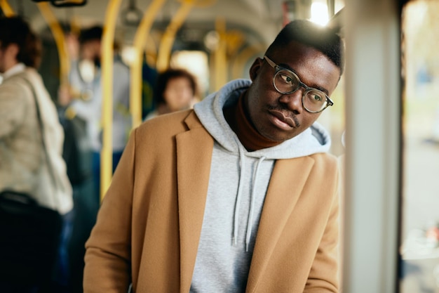 Homem negro pensativo, apoiando-se em uma janela enquanto viaja de ônibus