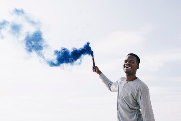 Homem negro segurando bombas de fumaça azuis