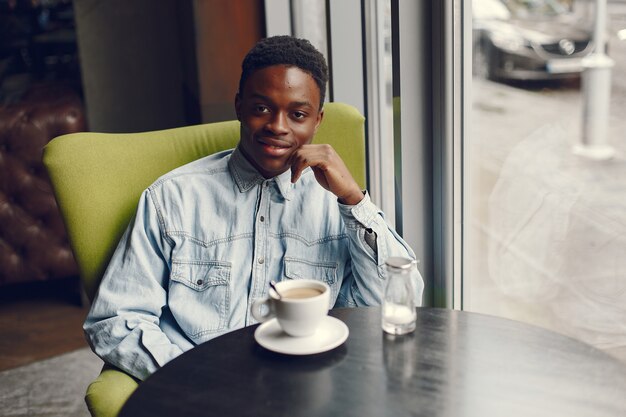 Homem negro sentado em um café e tomando um café