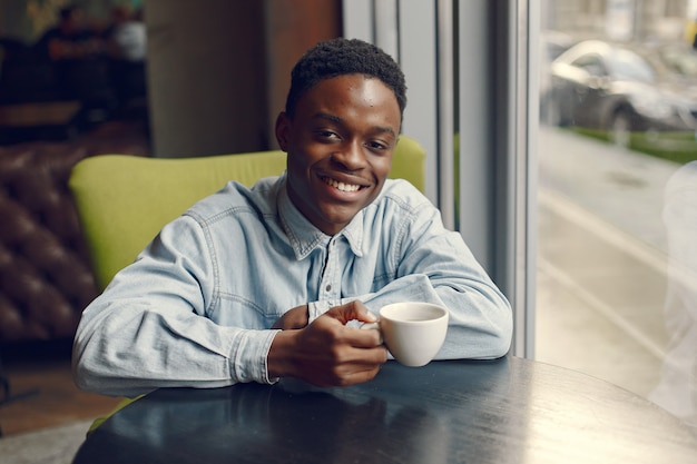 Homem negro sentado em um café e tomando um café