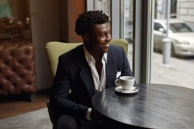 Homem negro sentado em um café e tomando um café