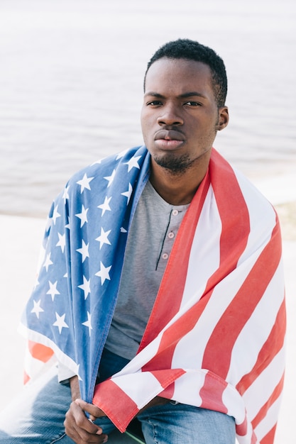 Homem negro sério envolto na bandeira americana