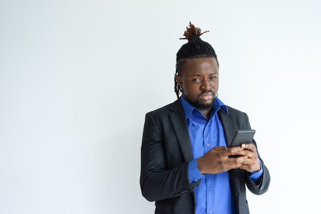 Homem negro sério segurando e usando o smartphone