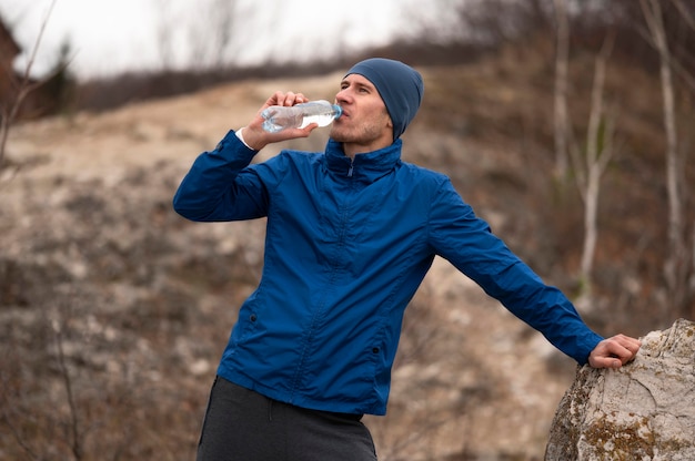 Foto grátis homem no meio do tiro bebendo água na natureza