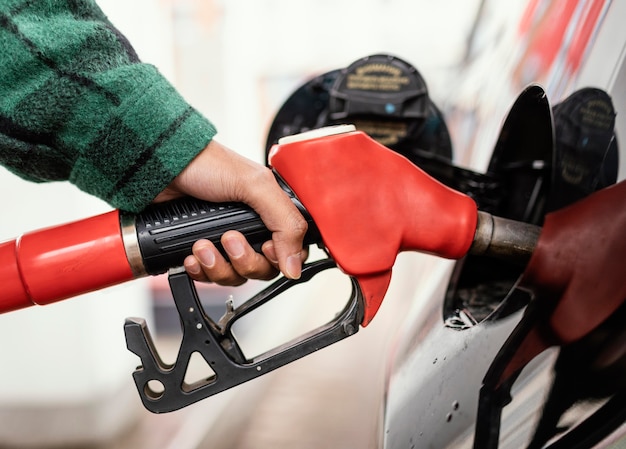 Homem no posto de gasolina com o carro de perto