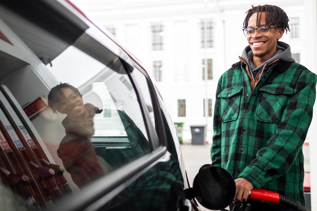 Homem no posto de gasolina com o carro