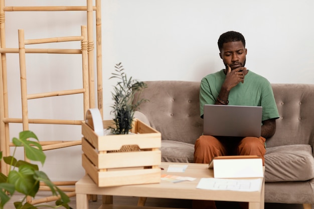 Homem no sofá fazendo um plano para redecorar a casa usando um laptop