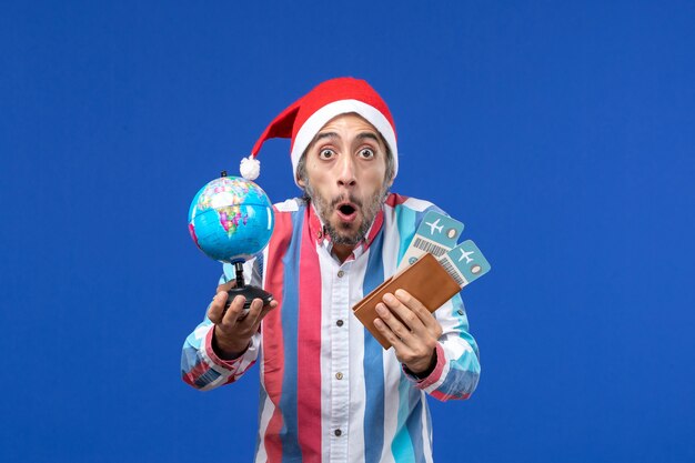 Homem normal de vista frontal com ingressos e globo no piso azul, cor do feriado de ano novo