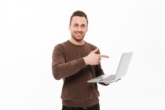 Homem novo de sorriso que aponta apontando do laptop.