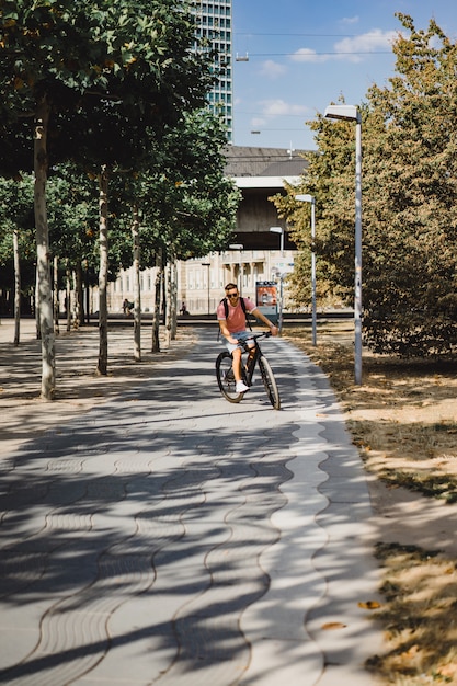 Homem novo dos esportes em uma bicicleta em uma cidade européia. Esportes em ambientes urbanos.