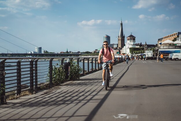 Homem novo dos esportes em uma bicicleta em uma cidade européia. Esportes em ambientes urbanos.