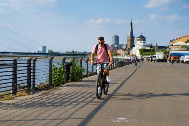 Homem novo dos esportes em uma bicicleta em uma cidade européia. Esportes em ambientes urbanos.