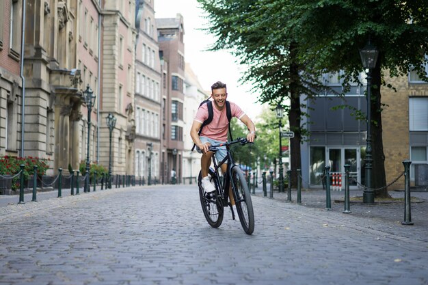 Homem novo dos esportes em uma bicicleta em uma cidade européia. Esportes em ambientes urbanos.