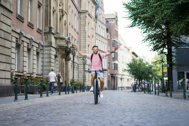 Homem novo dos esportes em uma bicicleta em uma cidade européia. Esportes em ambientes urbanos.