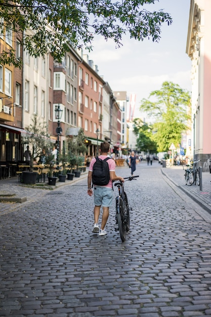 Homem novo dos esportes em uma bicicleta em uma cidade européia. Esportes em ambientes urbanos.