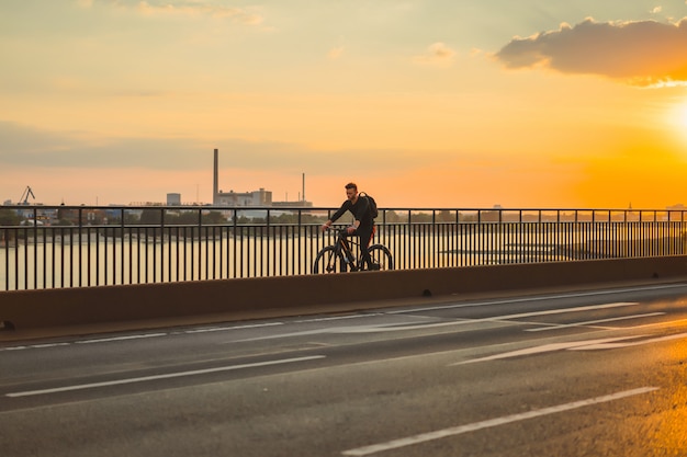 Homem novo dos esportes em uma bicicleta em uma cidade européia. Esportes em ambientes urbanos.