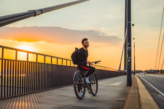 Homem novo dos esportes em uma bicicleta em uma cidade européia. Esportes em ambientes urbanos.