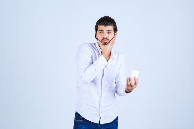 Homem olhando para sua xícara de café e mostrando uma expressão confusa