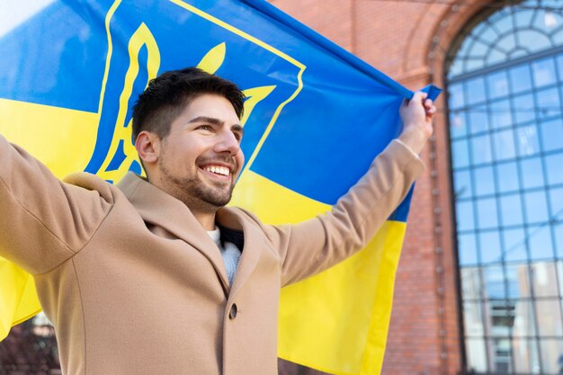 Homem orgulhoso segurando a bandeira ucraniana tiro médio