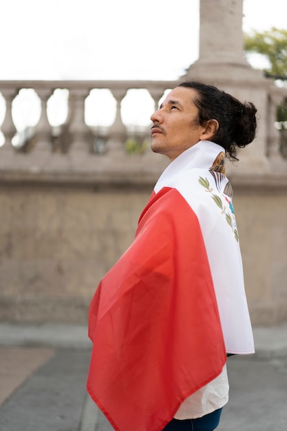 Foto grátis homem orgulhoso, vestindo vista lateral da bandeira mexicana