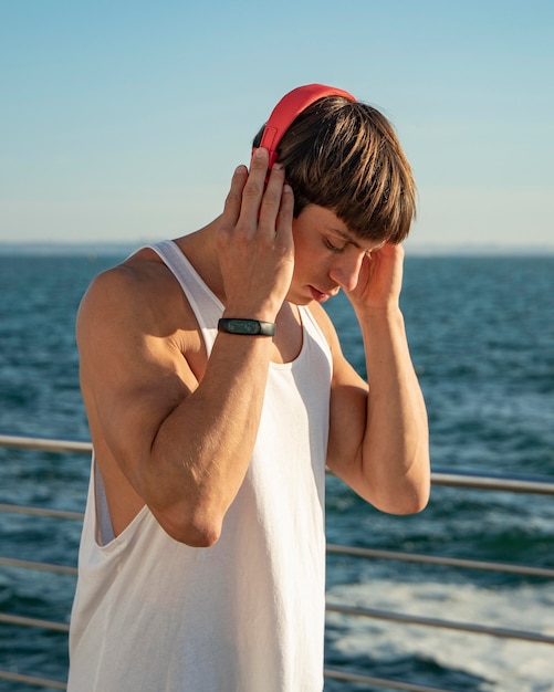 Homem ouvindo música na praia enquanto faz exercícios