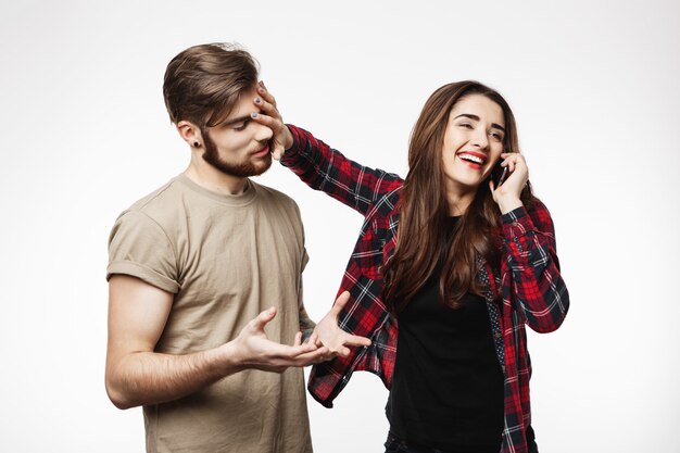 Homem pedindo para a mulher parar de falar no telefone, parecendo cansado.