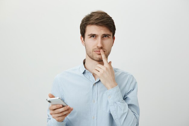 Homem pensativo ponderando usando telefone celular, olhar para cima pensando