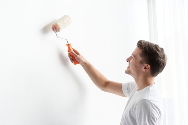 Foto grátis homem pintando sua parede de branco