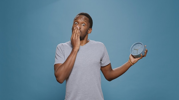 Homem pontual chocado, verificando o tempo no relógio e atrasado para o trabalho, sentindo-se estressado com o atraso do prazo. Pessoa surpreendida com pressa olhando para horas e minutos no instrumento de relógio.