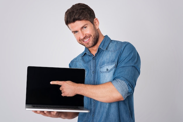 Homem posando com camisa jeans e laptop