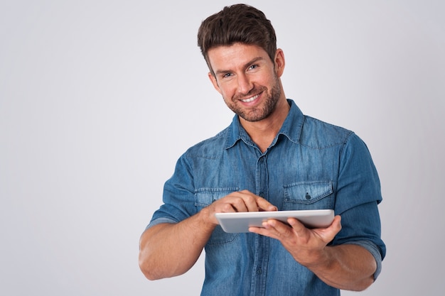 Foto grátis homem posando com camisa jeans e tablet