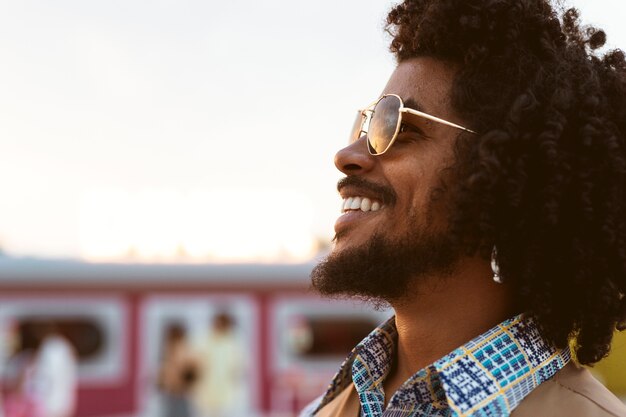 Homem posando em estilo retrô ao ar livre com óculos de sol