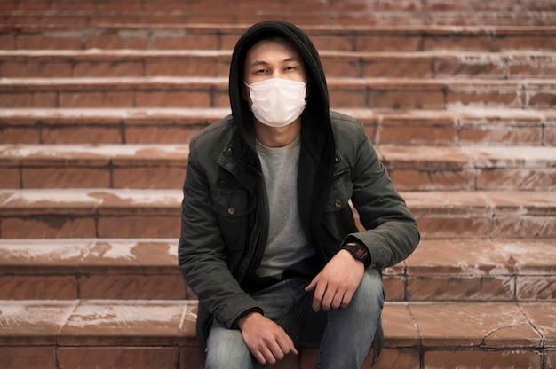 Homem posando na escada enquanto usava máscara médica