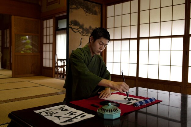Homem praticando caligrafia japonesa com pincel e tinta