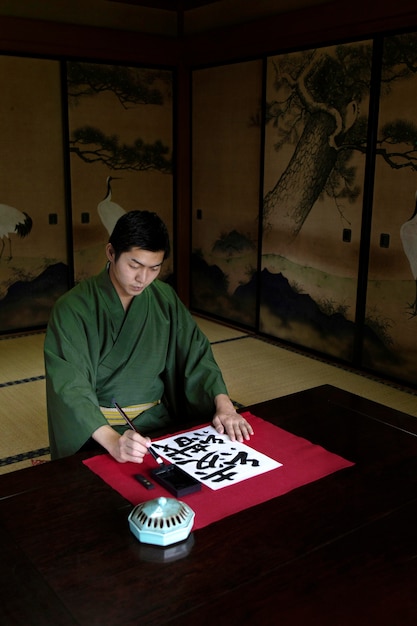 Foto grátis homem praticando caligrafia japonesa com pincel e tinta