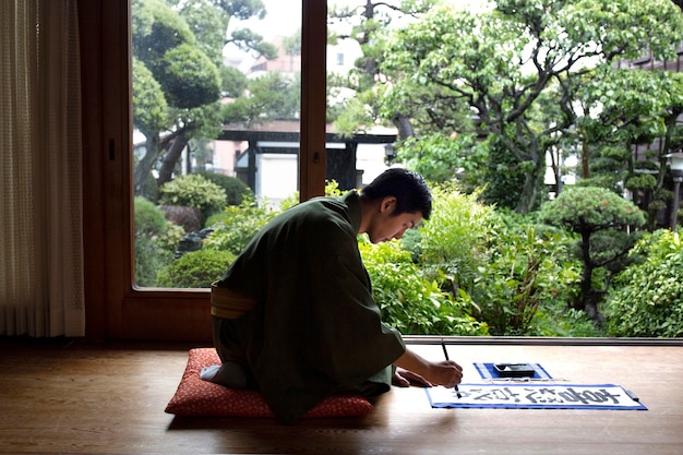 Homem praticando caligrafia japonesa com pincel e tinta
