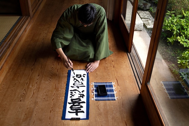 Homem praticando caligrafia japonesa com pincel e tinta