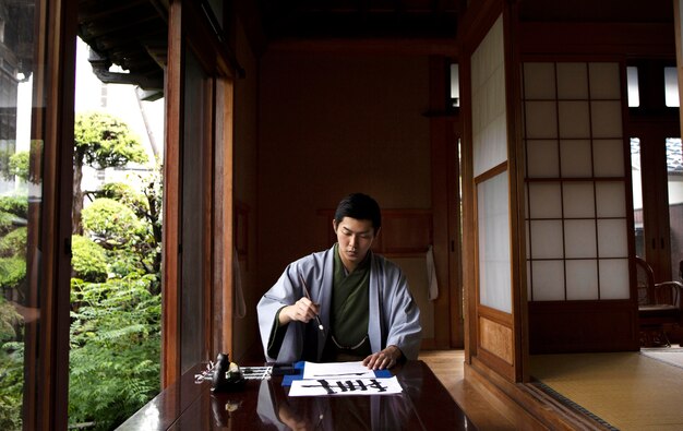 Homem praticando caligrafia japonesa com um pincel